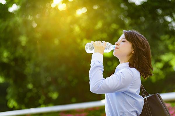 Jeune femme qui boit de l'eau dans une bouteille en plastique