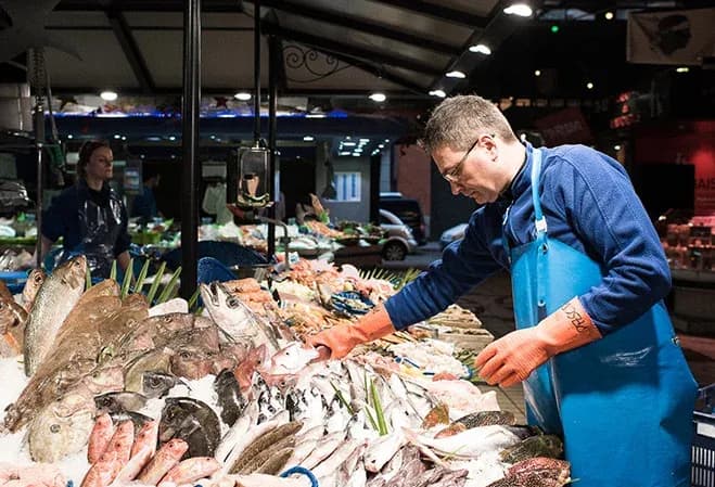 vendeur de poisson sélectionnant des produits frais sur un étal de marché en soirée