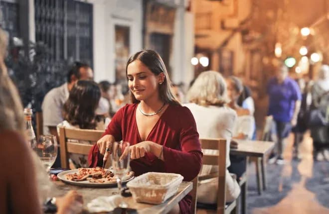 jeune femme dégustant une pizza en terrasse animée le soir