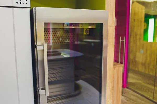 armoire réfrigérée vitrée avec étagères métalliques dans un intérieur coloré