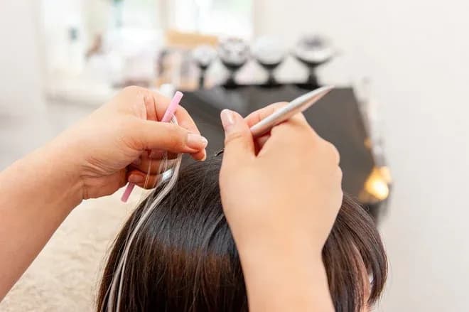 Application de mèches sur des cheveux avec des outils de coiffure dans un salon.