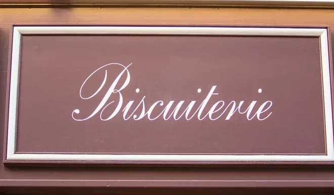 enseigne d'une biscuiterie avec le mot Biscuiterie en lettres cursives blanches sur fond marron