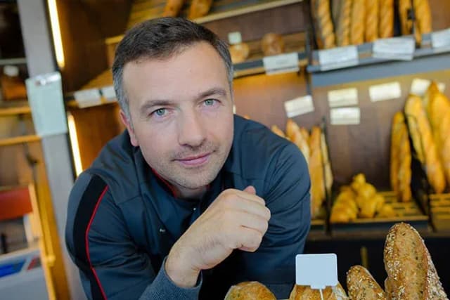 boulanger appuyé au comptoir devant des pains et baguettes