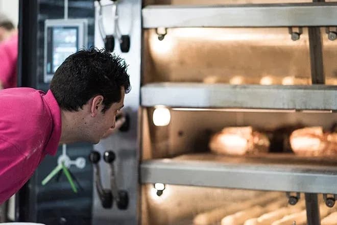boulanger regardant des pains dans un four professionnel