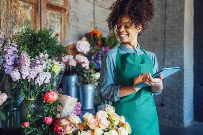 fleuriste souriante devant des bouquets de fleurs dans une boutique lumineuse