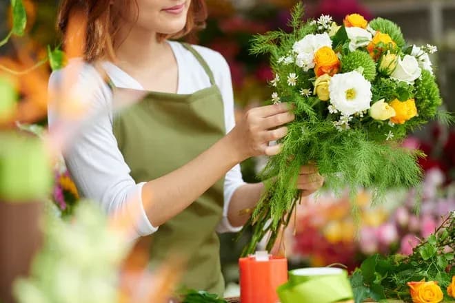 femme en train de composer un bouquet de fleurs colorées dans un atelier floral