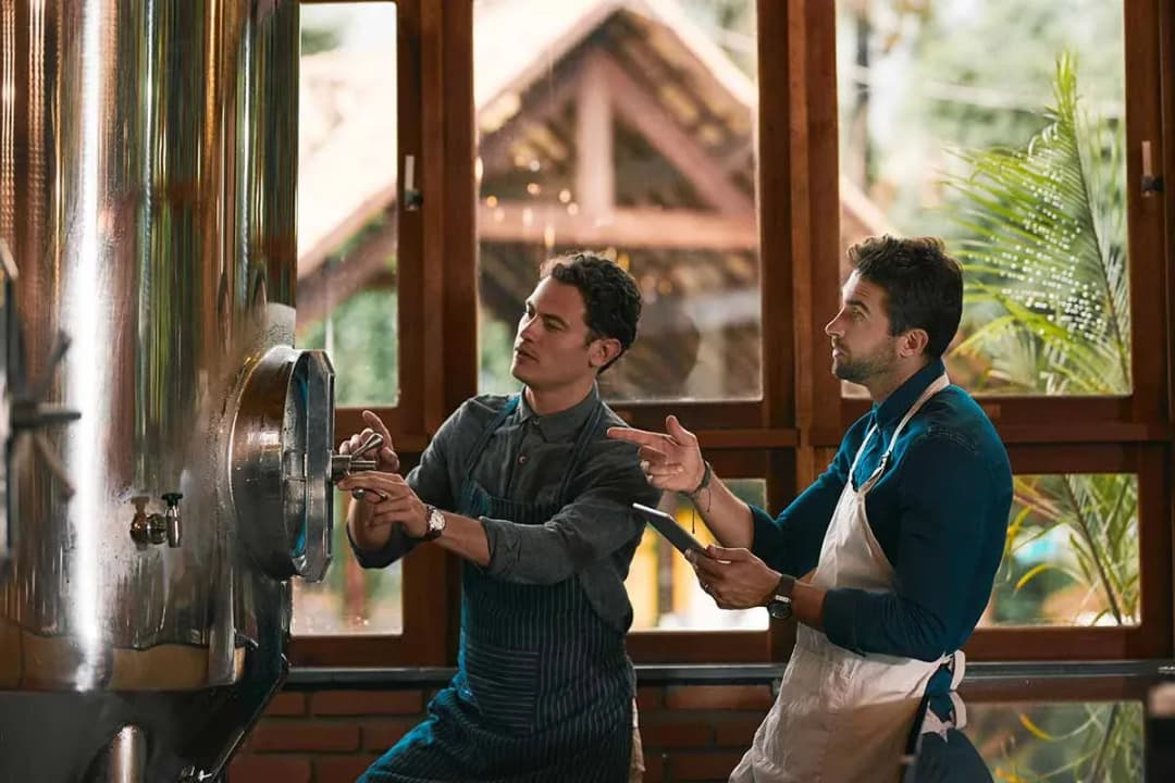 deux brasseurs ajustent une cuve inox et l'un consulte une tablette