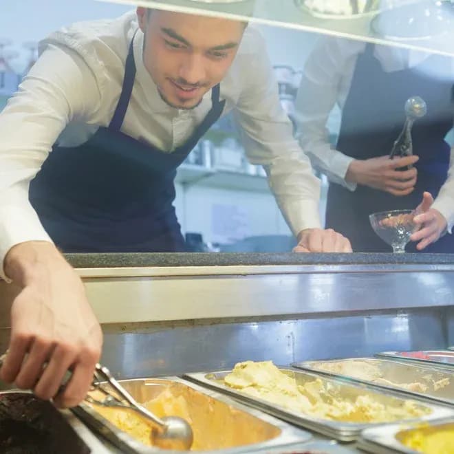 serveur prenant une boule de glace dans une vitrine avec plusieurs parfums visibles