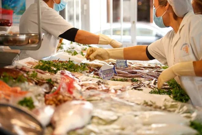 vendeurs préparant des produits de la mer sur un étal garni de poissons et crustacés