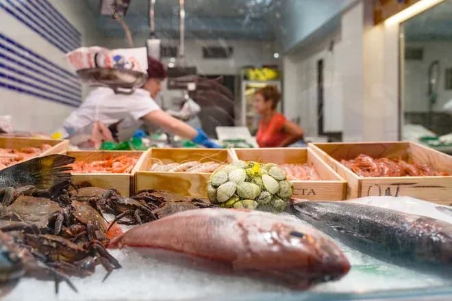 étal de poissonnerie avec divers fruits de mer et poisson frais en arrière-plan