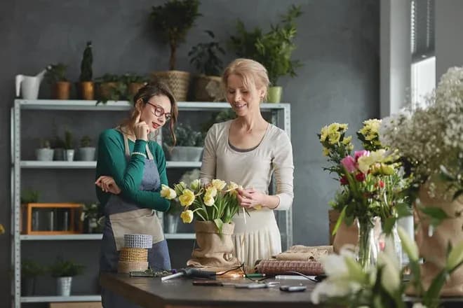 deux femmes discutent en créant des arrangements floraux dans un atelier lumineux et verdoyant