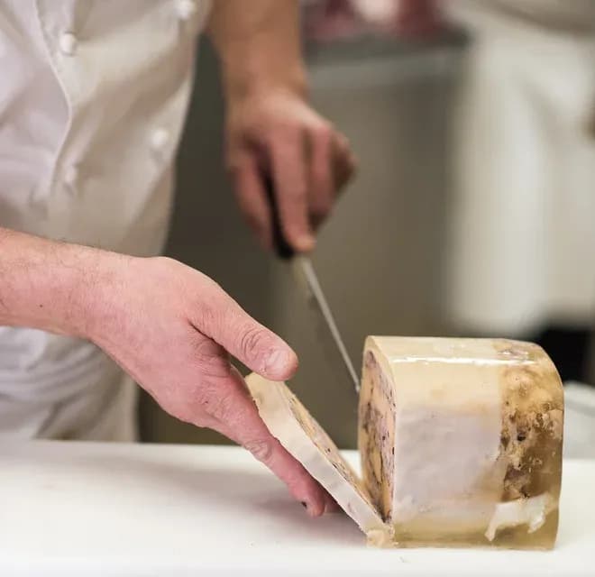 charcutier tranchant une terrine en gelée