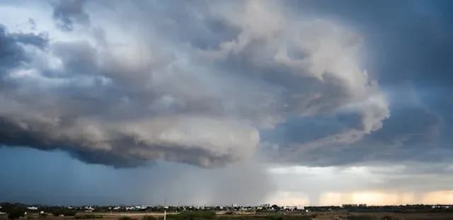 ciel orageux avec nuages tourbillonnants et rideaux de pluie au-dessus d'un village