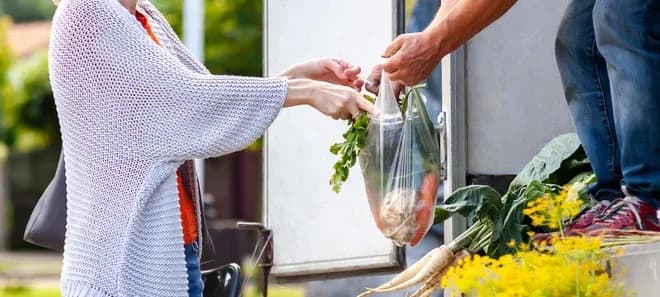 Échange de légumes frais entre un vendeur et un client sur un marché.