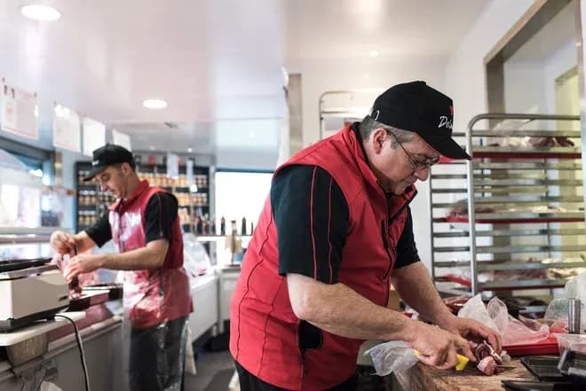 bouchers en train de préparer de la viande dans une boucherie moderne et bien éclairée