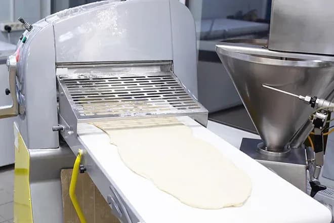 pâte laminée sortant d'une façonneuse sur convoyeur