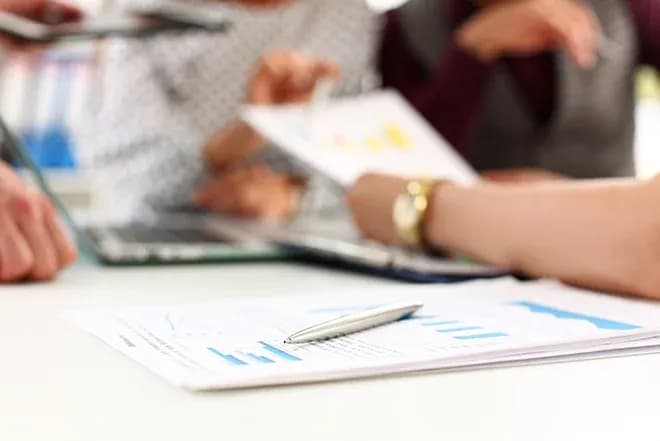 documents de travail et graphiques sur une table avec des personnes en discussion