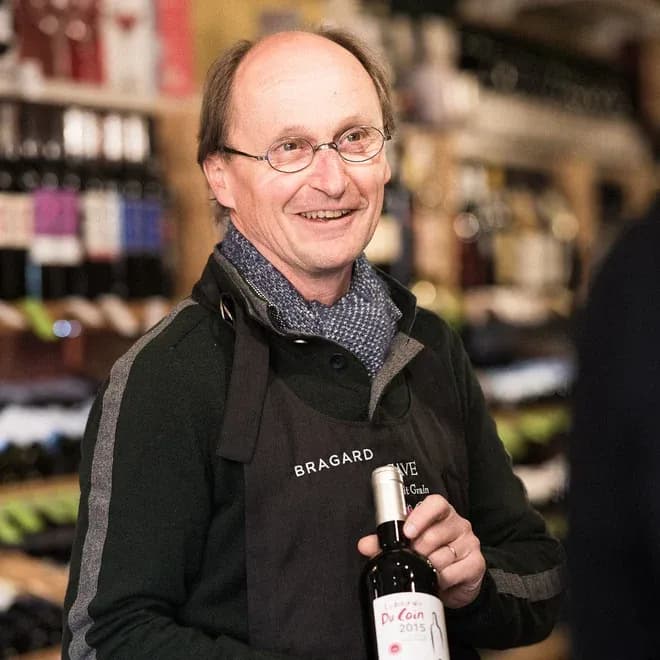 caviste souriant présentant une bouteille de vin en boutique