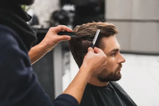 coiffeur en train de couper les cheveux d'un homme dans un salon de coiffure moderne