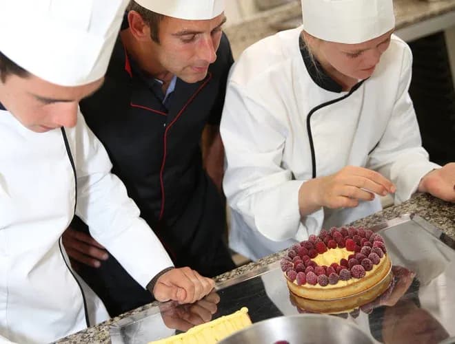 apprentis pâtissiers préparant et décorant une tarte aux framboises