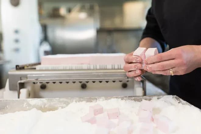 Préparation de morceaux de guimauve dans un atelier de confiserie avec du sucre en poudre
