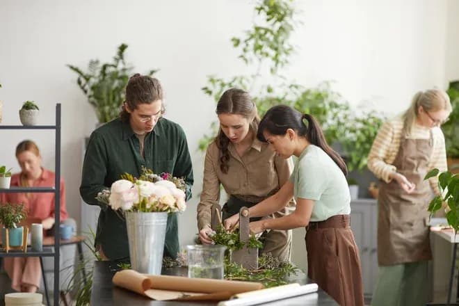 trois stagiaires créant un bouquet lors d'un atelier de fleuristerie