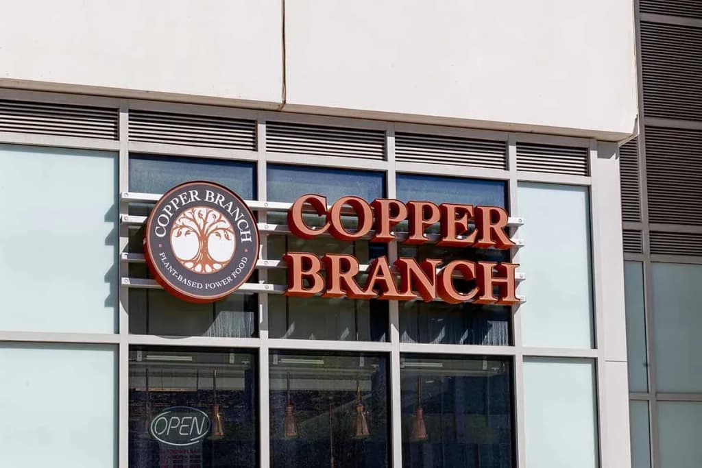 enseigne Copper Branch en lettres orange et logo rond sur façade vitrée