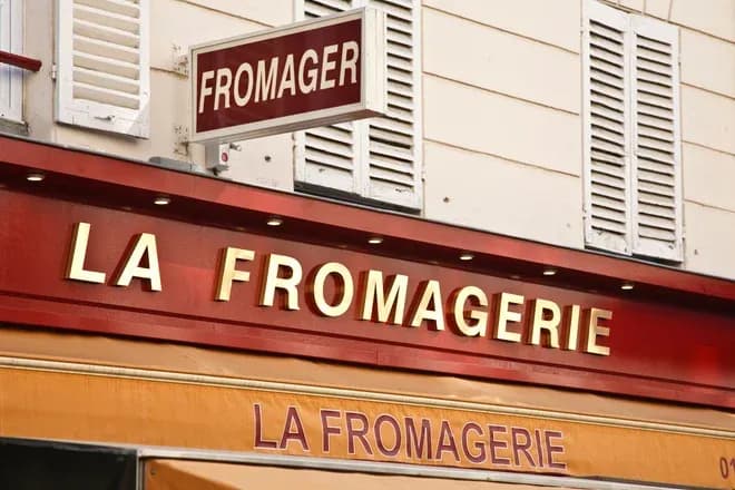 enseigne d'une fromagerie avec le nom en lettres dorées sur fond rouge
