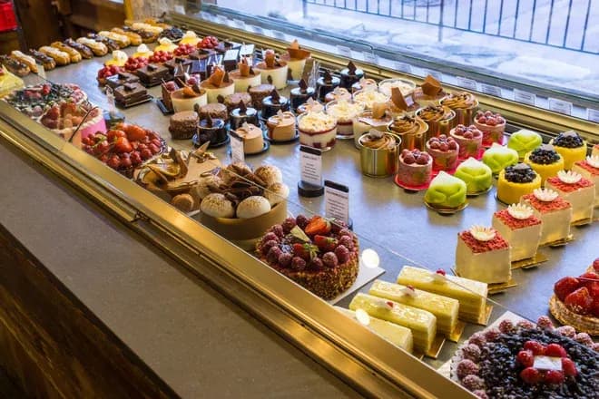 vitrine de pâtisserie avec assortiment d'entremets colorés et fruits