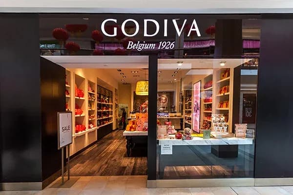 boutique Godiva avec vitrines et étagères remplies de chocolats colorés