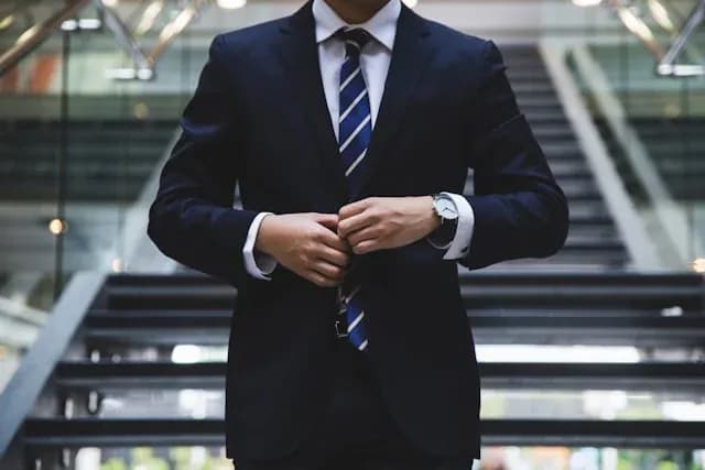 Homme en costume ajustant sa cravate dans un environnement moderne et professionnel