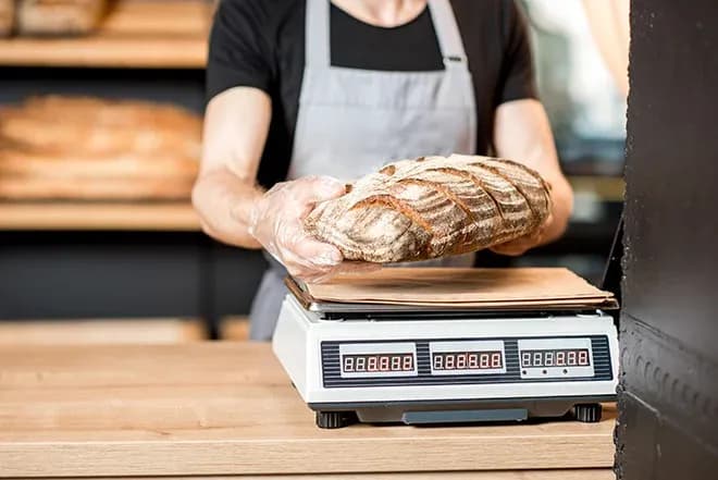 boulanger pèse une miche de pain sur une balance