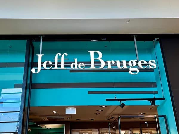 enseigne d'un magasin Jeff de Bruges sur fond turquoise avec des éléments de décoration moderne