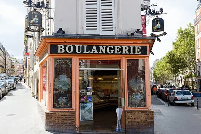 boulangerie avec une devanture orange et des panneaux décoratifs sur une rue animée