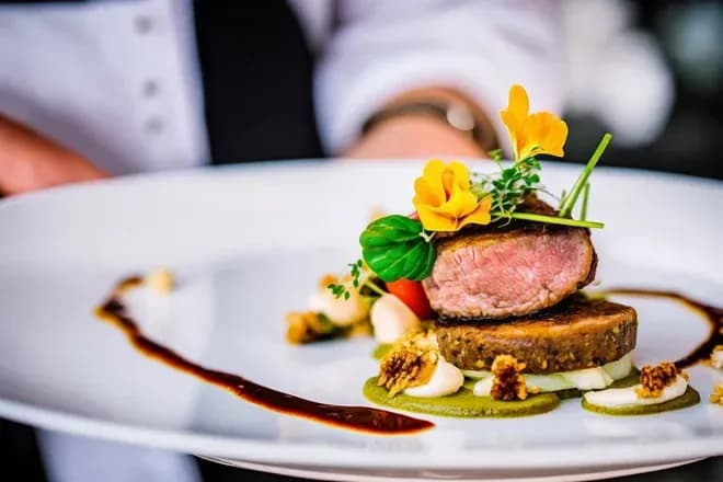 médaillon de viande rosé garni de fleurs comestibles purée et réduction de sauce