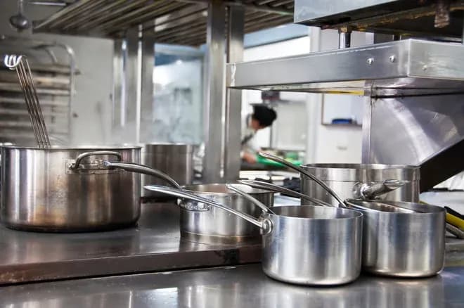 ustensiles et casseroles en inox sur plaque de cuisson d'une cuisine professionnelle