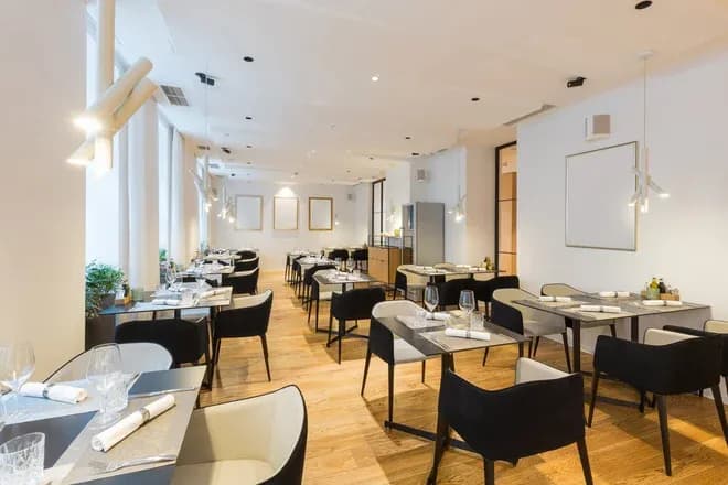 salle de restaurant lumineuse avec tables dressées et chaises noires