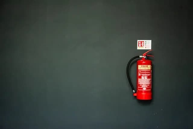 extincteur à mousse rouge fixé sur mur gris avec panneau de sécurité