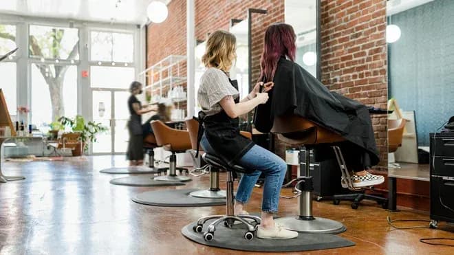 coiffeuse s'occupant d'une cliente dans un salon de coiffure moderne et lumineux