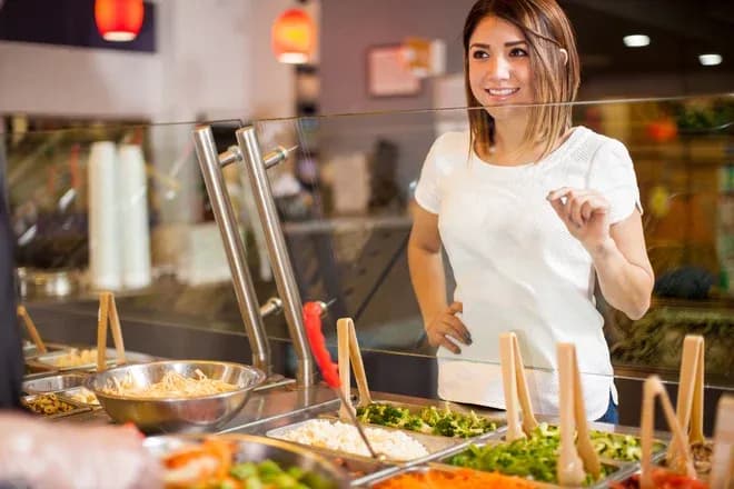 femme souriante choisissant des garnitures à un bar à salades
