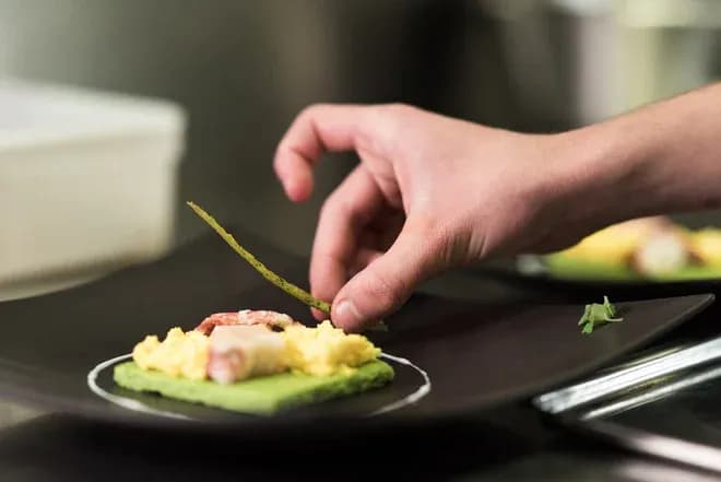 main d'un chef dressant un plat gastronomique