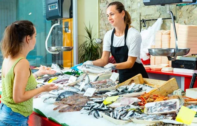 Vendeuse de poisson présente des produits frais à une cliente dans un marché animé