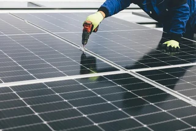 technicien installant des panneaux solaires avec une perceuse sur un toit