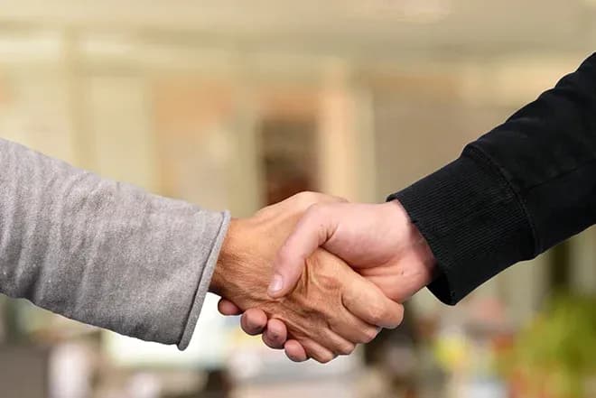 poignée de main entre deux personnes dans un cadre professionnel flou en arrière-plan