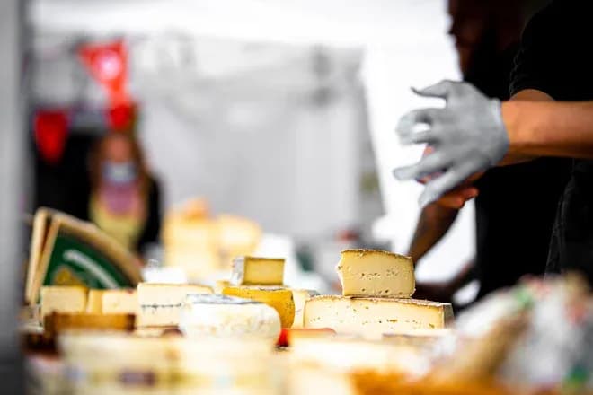 fromager avec plusieurs types de fromage sur une table à un marché