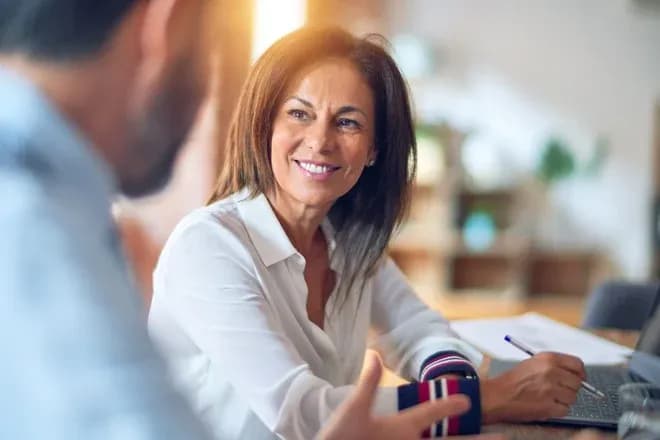 femme souriante en conversation avec un homme dans un bureau lumineux et chaleureux