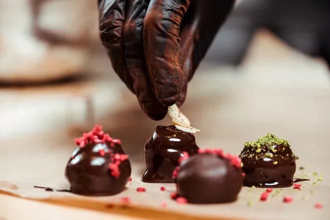 main-d'œuvre en chocolat avec garniture sur des bonbons artisanaux sur un plan de travail