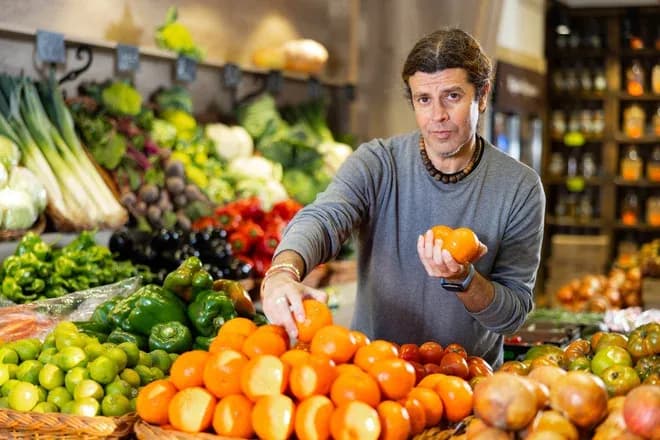 primeur range des clémentines sur un étal de fruits et légumes