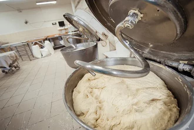 mélange de pâte à pain dans un pétrin en boulangerie avec un plan de travail en arrière-plan
