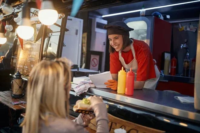 serveuse souriante prenant une commande dans un food truck avec des condiments en arrière-plan